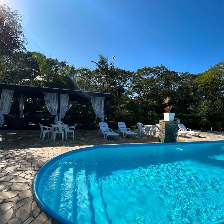 una grande piscina con sedie e un patio di Recanto Carvalho - Suíte 2 a Itapoa