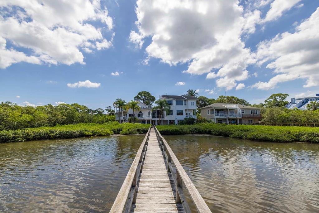 eine Holzbrücke über einen Fluss mit Häusern in der Unterkunft 4B Waterfront Game Room Pool Hot Tub Dock in Palm Harbor