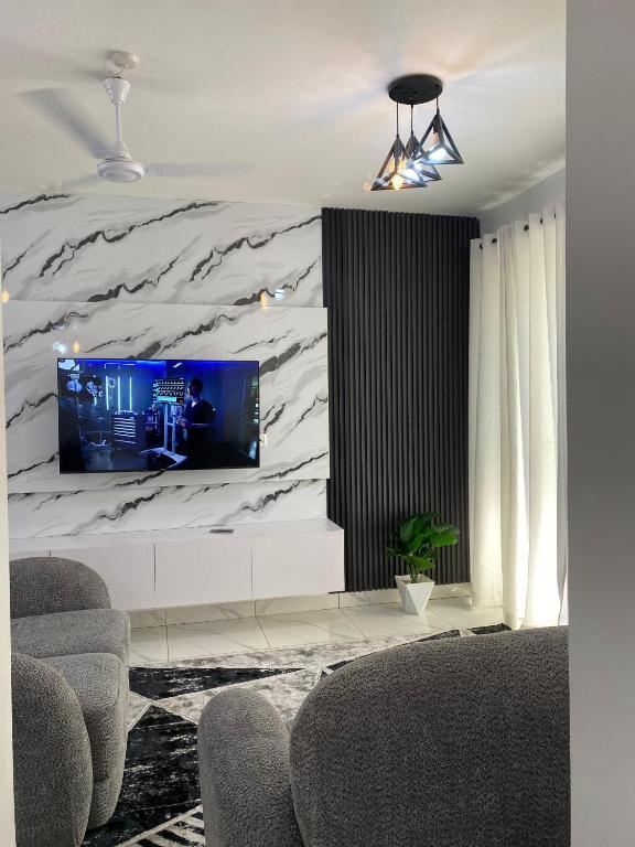 a living room with a tv on a marble wall at High Tide BnB Apartment in Mombasa