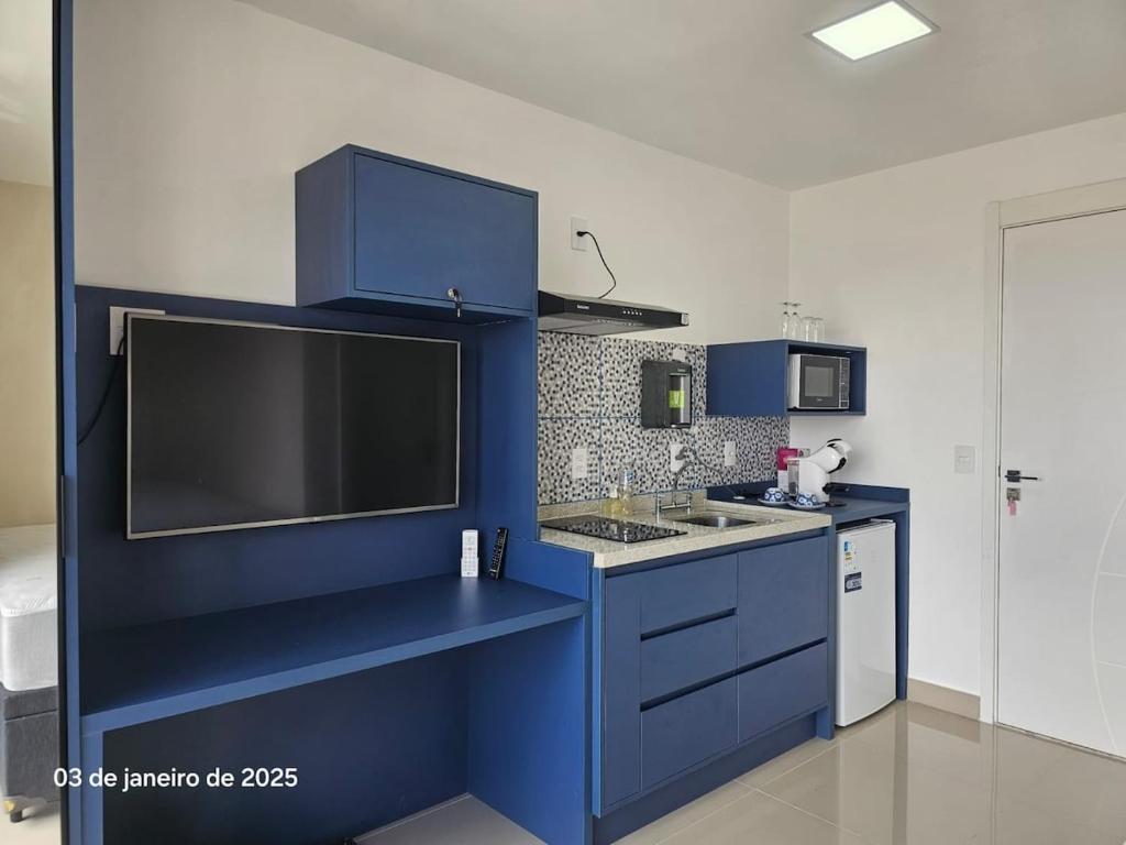 a kitchen with blue cabinets and a large tv at Studio | Expo Stay Tucuruvi Metro |Swimming pool in São Paulo