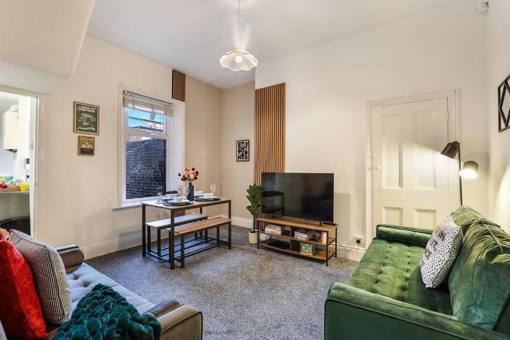 a living room with a green couch and a television at Entire Home- Parking - Fibre Broadband - Air Fryer - Big TV - 4 bedrooms - 8 guests in Elswick
