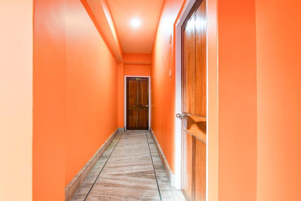a corridor with orange walls and a hallway with a door at Hotel O De Sikkim Regency in Gangtok