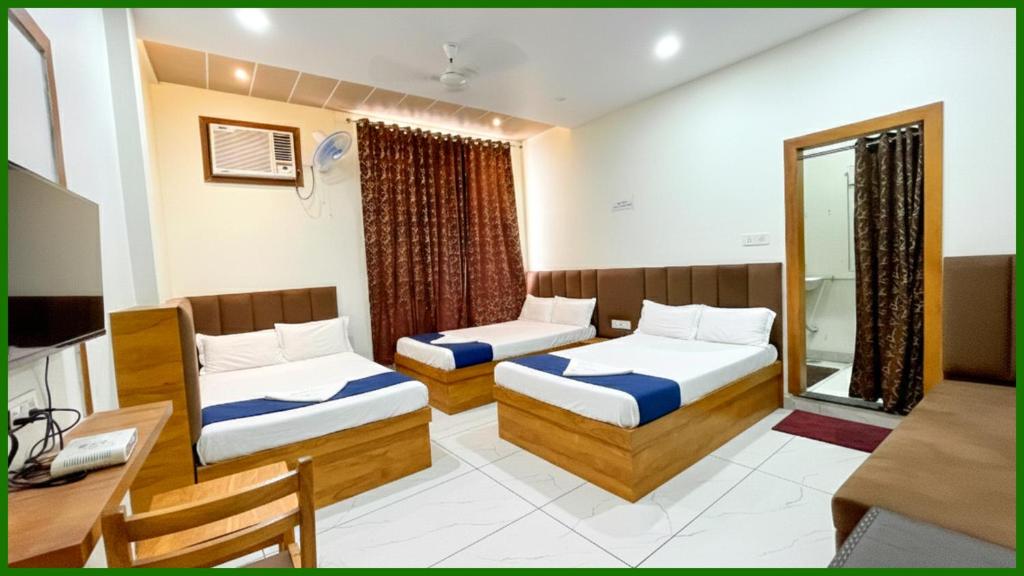 Una habitación de hotel con dos camas y un escritorio. en Near Mahakal Temple G- Residency Near Railway Station - Air Conditioned hotel at Prime Location - Lift and Parking - BEST HOTEL IN UJJAIN, en Ujjain