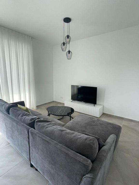 Una sala de estar con un sofá y un televisor de pantalla plana. en Elite 1BD Flat with Pool in Harbor area, en Lárnaca