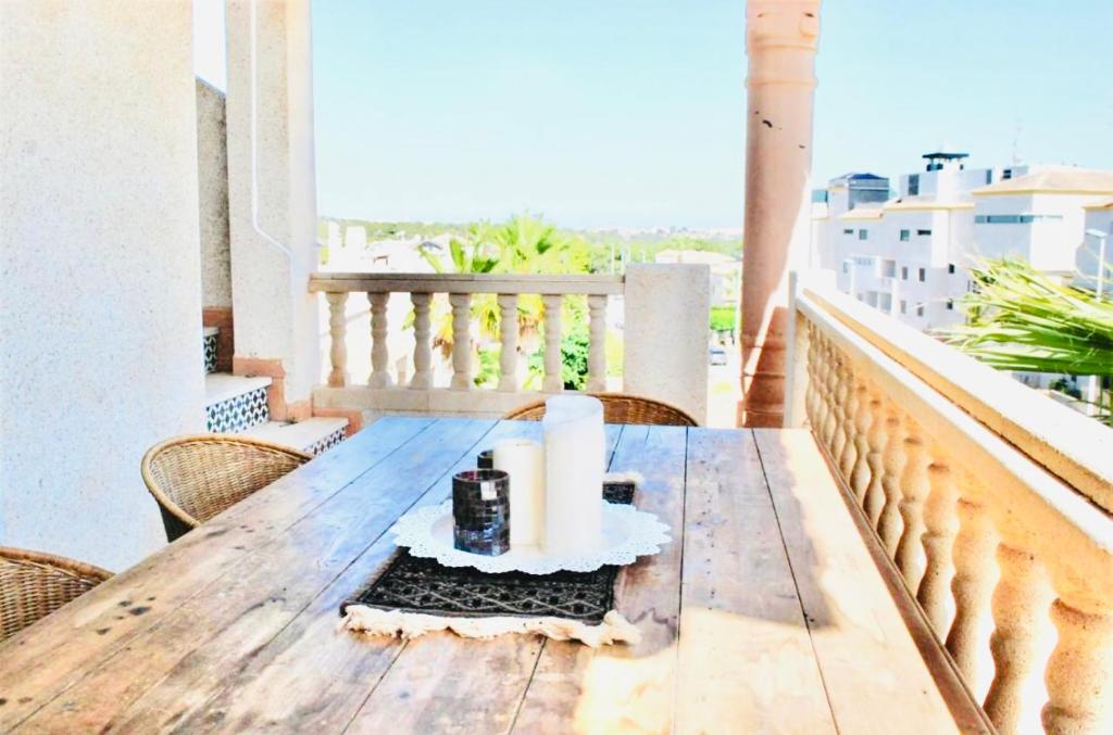 een houten tafel op een balkon met kaarsen erop bij Private Solarium - Golf and Pool View - Las Ramblas 830 in Orihuela-Costa
