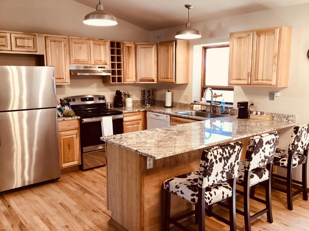 une cuisine avec des armoires en bois et un réfrigérateur en acier inoxydable dans l'établissement Durango Colorado Four Bedroom Two Bathroom Home, à Durango