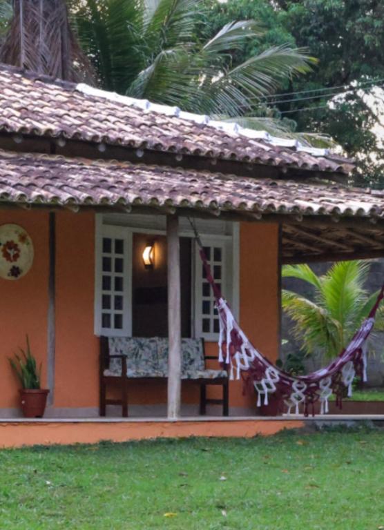 a house with a hammock in front of it at Casa Coqueville - Charmosa, tranquila e cercada pela natureza em Itacaré in Itacaré