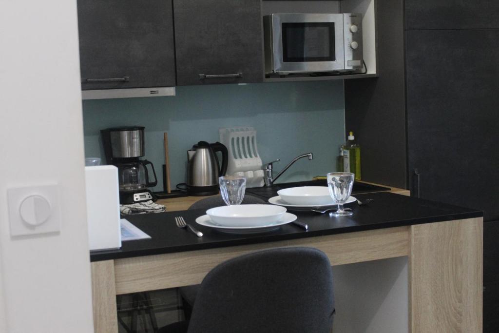 a kitchen with a table with two plates and a microwave at Le Ty Logis in Vannes