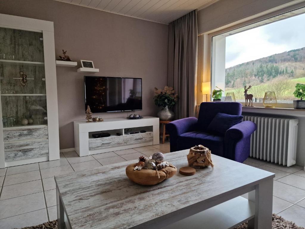 a living room with a table and a tv at Hirschblick Apartments Willingen in Brilon