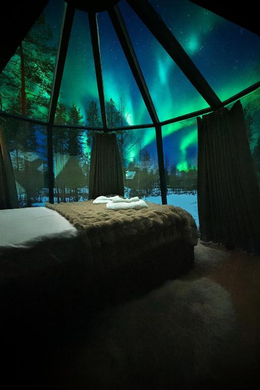 a room with a bed with a view of the northern lights at Arctic Bear Resort - Lapland - Aurora suite - Sauna - Northern Lights in Ranua
