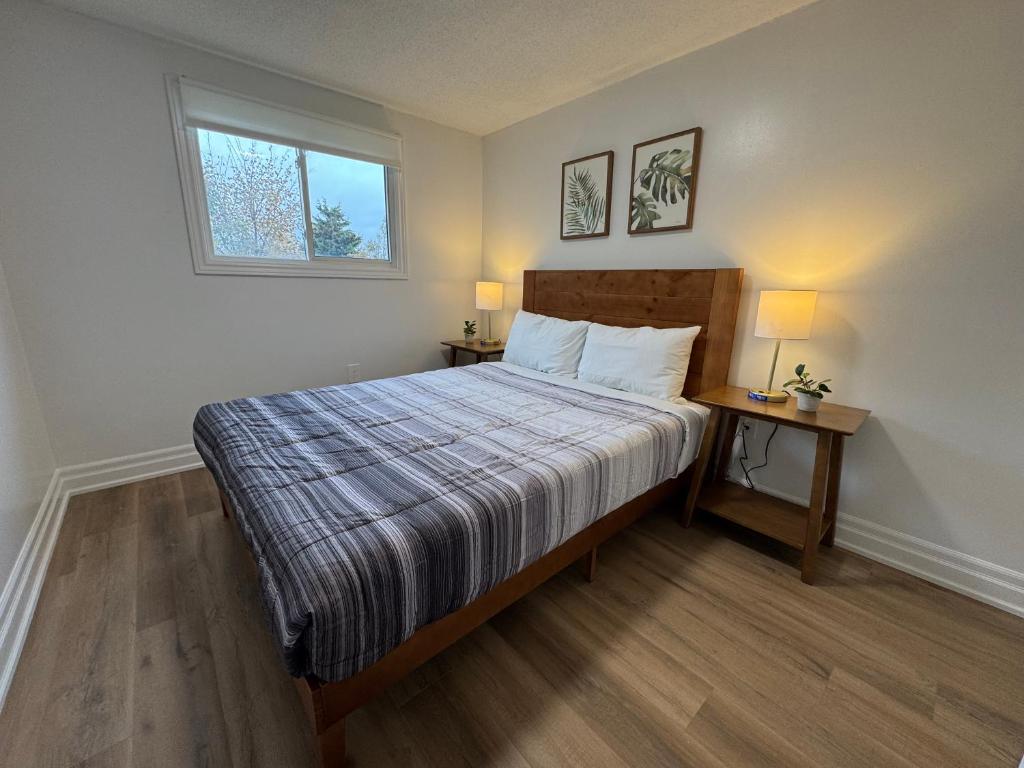a bedroom with a bed with two tables and a window at North Barrie !E Stylish and Cozy Private Bedroom with Shared Bathroom in Barrie