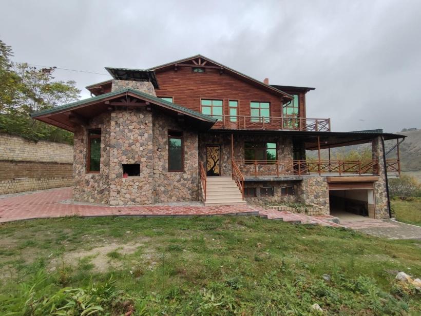 a large stone house with a porch and a balcony at The River View Villa الحلال Halal Concept in Quba