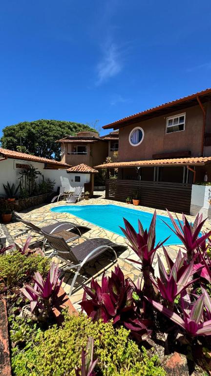 a swimming pool in front of a house with purple flowers at Solar del Mar in Praia do Rosa