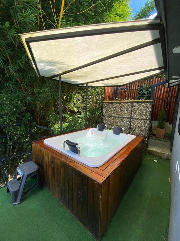 El PeñolRocks Glamping - Guatapé, El Peñol的院子里有一个带遮阳伞的木制浴缸。