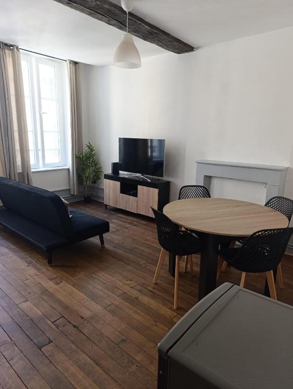 a living room with a table and a tv at Appartement Cosy du château in Sedan