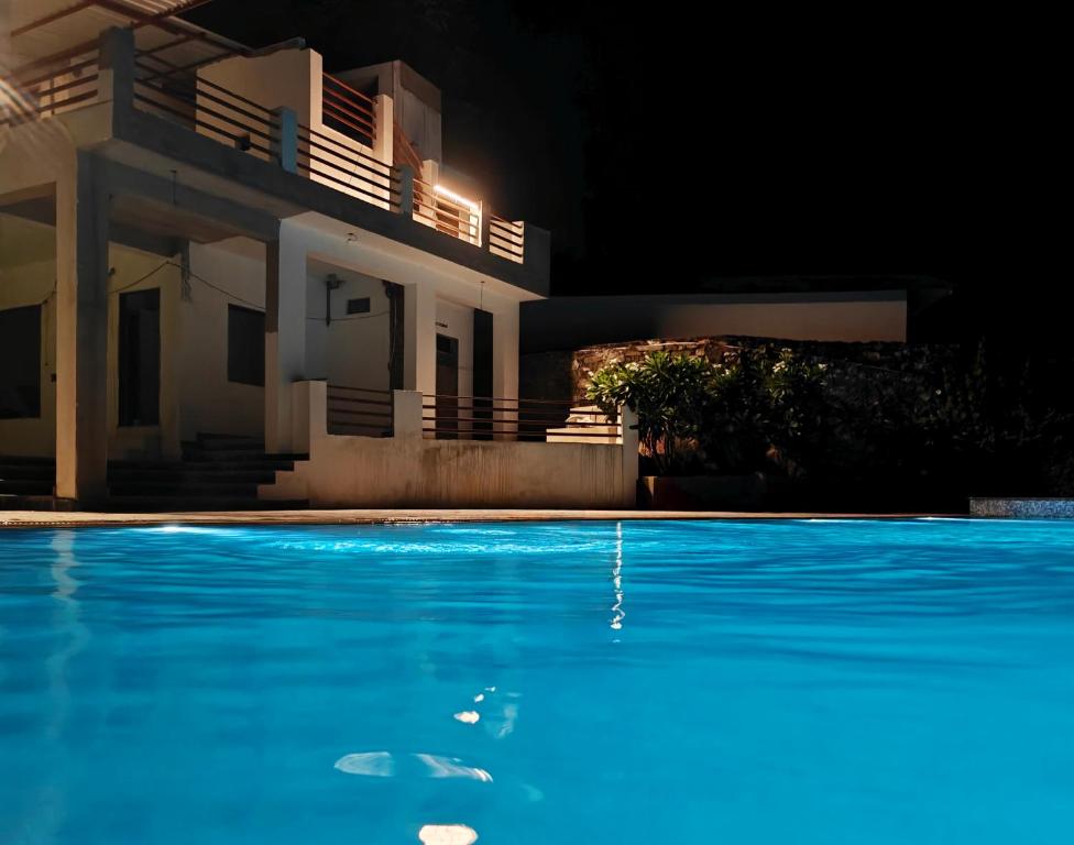 una piscina davanti a una casa di notte di The Jungle Gate Villa a Udaipur