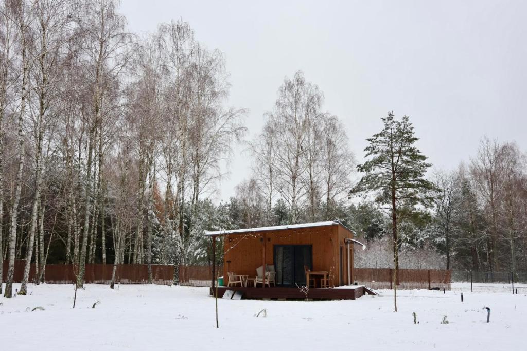Una pequeña cabaña en la nieve con una valla. en MISI domek, en Kadłubówka