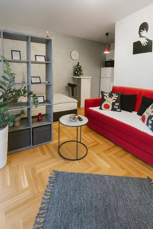 a living room with a red couch and a table at Studio IKA Belgrade Airport Free Parking possible Self Check-In Terrace in Ledine