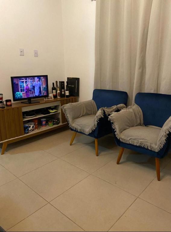 uma sala de estar com duas cadeiras e uma televisão em Casa com excelente acomodação em Itatiaia