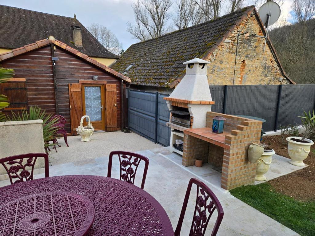 eine Terrasse mit einem Tisch und einem Grill im Hinterhof in der Unterkunft Le petit chalet in Gigouzac