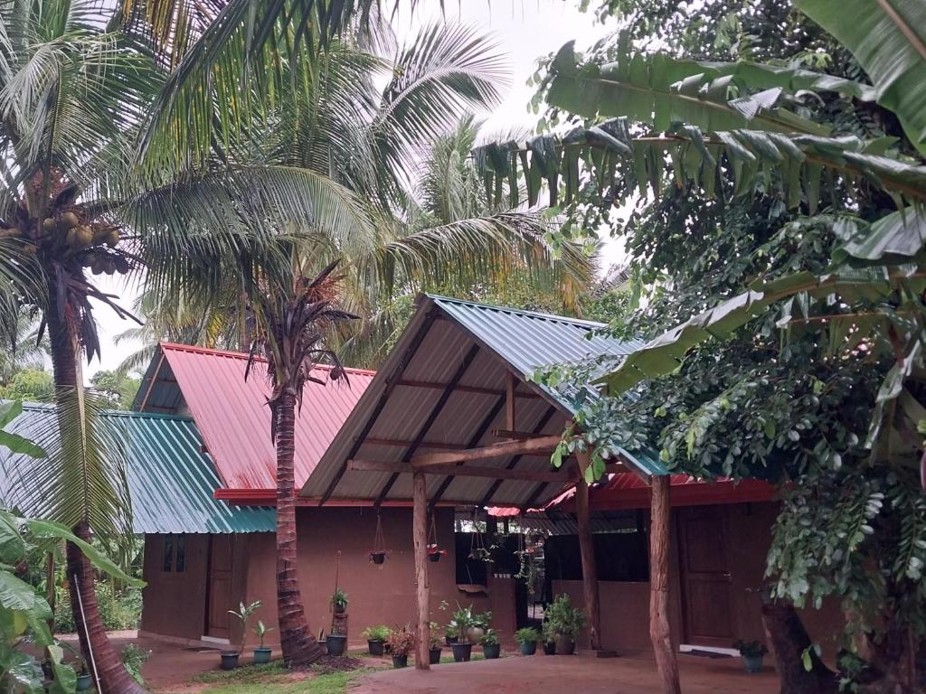 ein Gebäude mit einem roten Dach und einigen Palmen in der Unterkunft Amuna Villa in Habarana