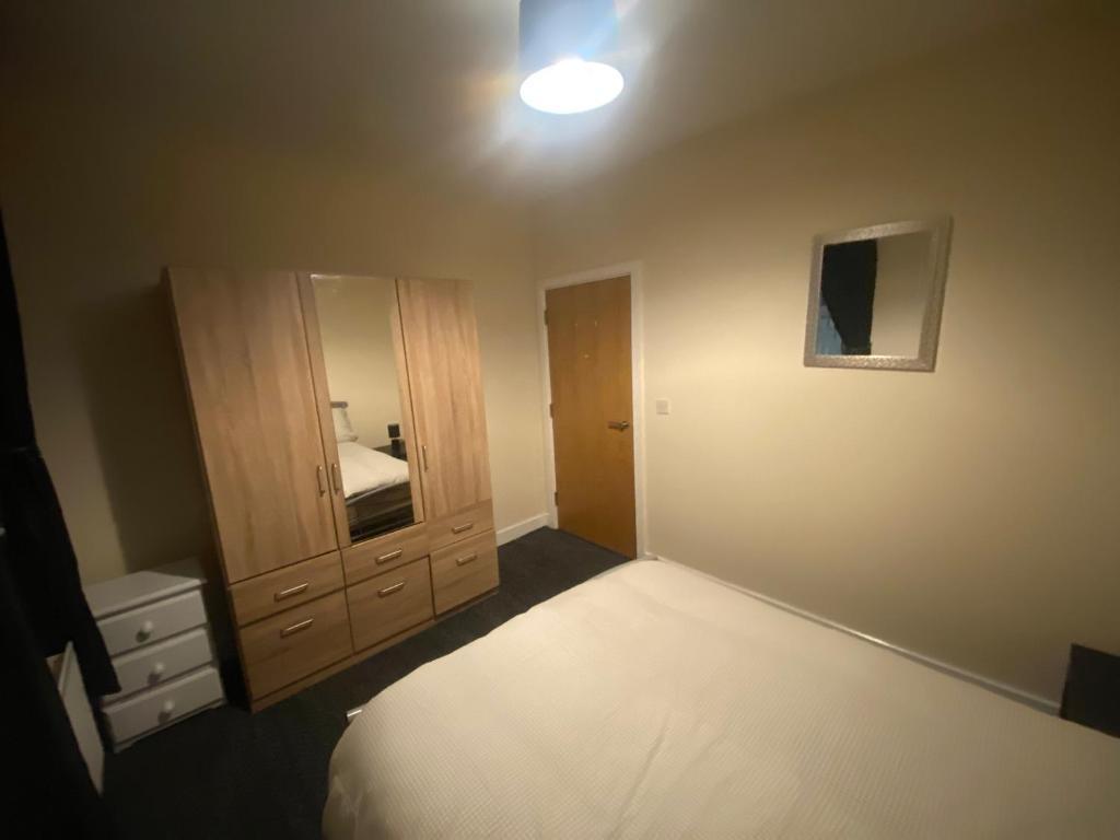 ein Schlafzimmer mit einem Bett, einer Kommode und einem Spiegel in der Unterkunft vancouver place 10 min from city center and close to all shops in Belfast
