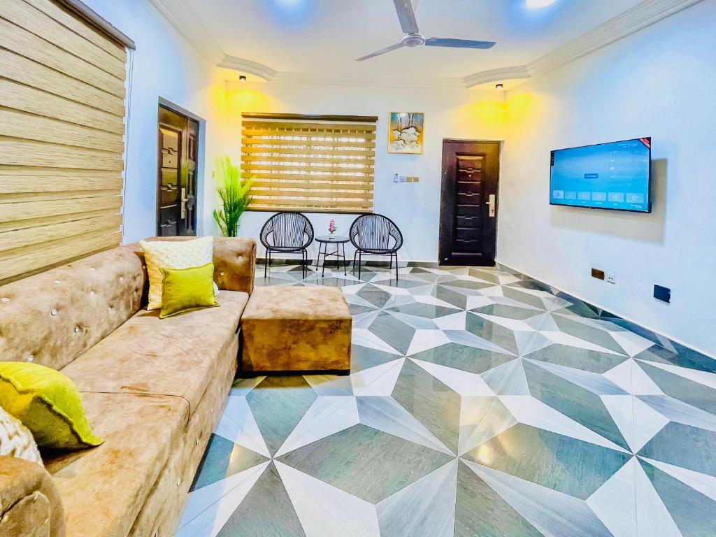 a living room with a couch and a tv at Caro Spacious Apartment for leisure stay in Accra