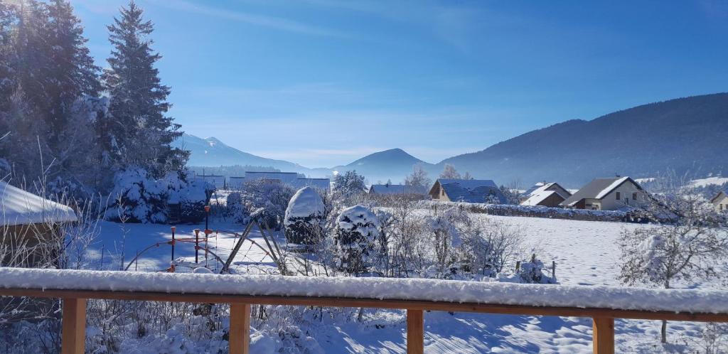 韦尔科尔地区朗Chez Mat的一座有房子和山 ⁇ 的雪覆盖的院子