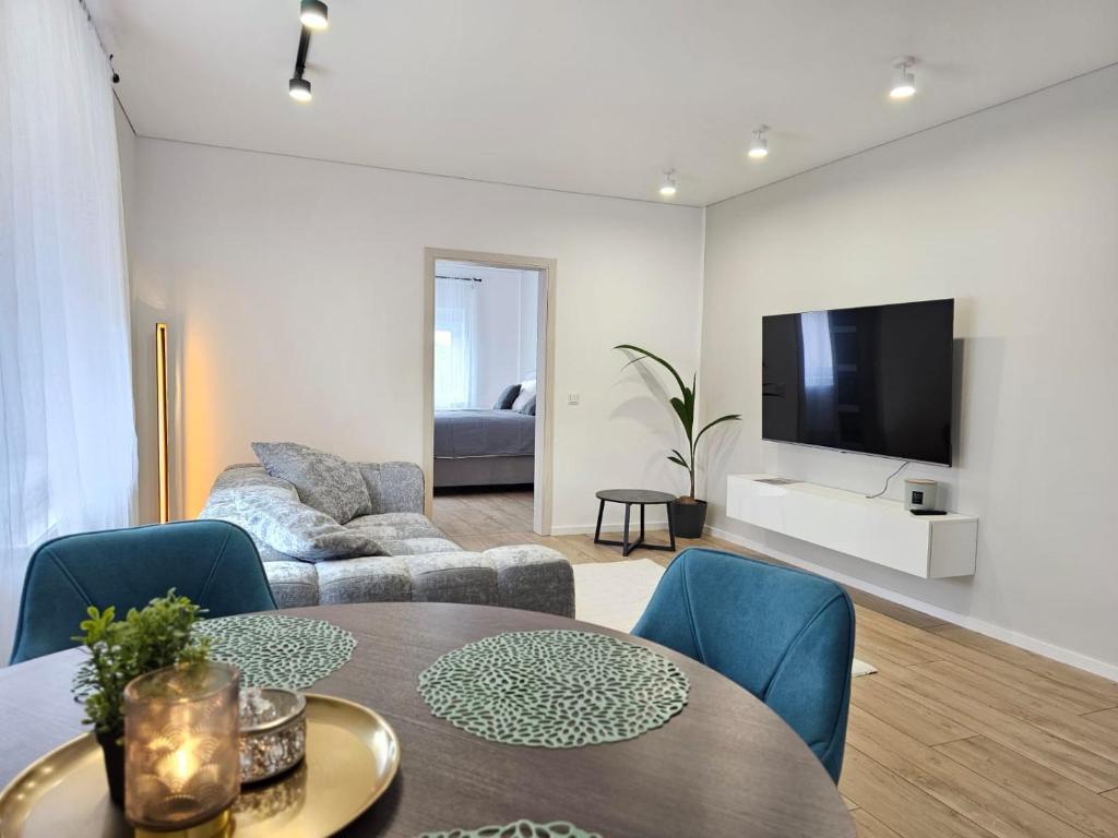 un soggiorno con tavolo, sedie e TV di Exklusive Wohnung im Herzen Ramsteins a Ramstein-Miesenbach