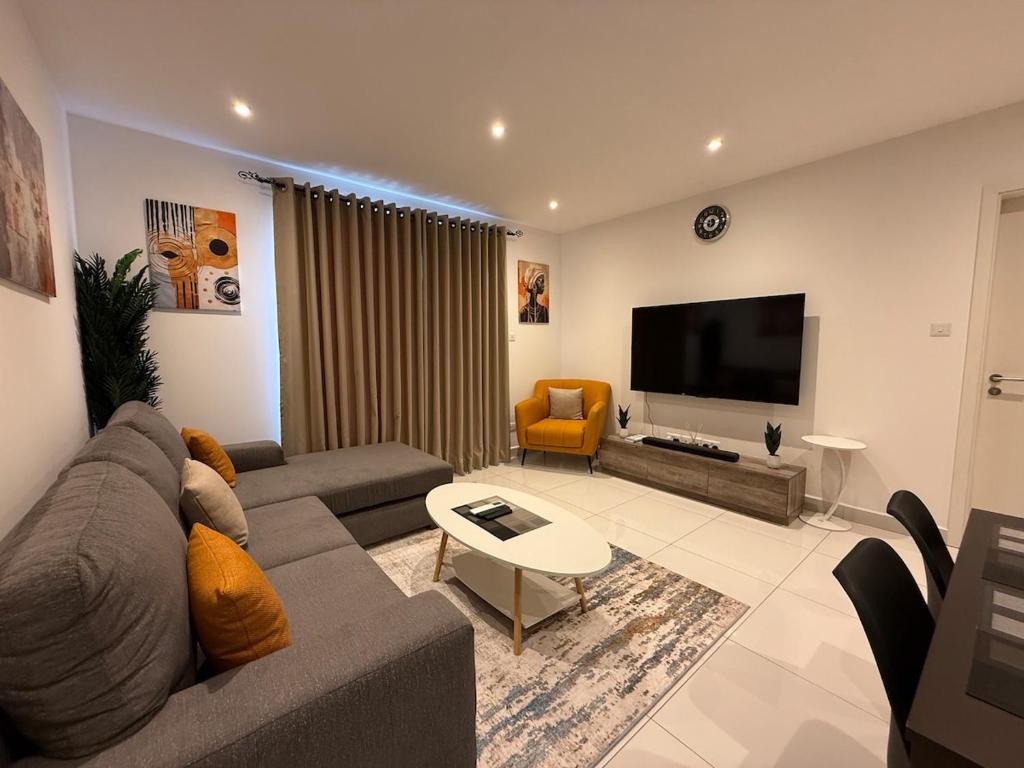 a living room with a couch and a flat screen tv at East Legon Loxwood House Condo with Gym & Pool in Accra