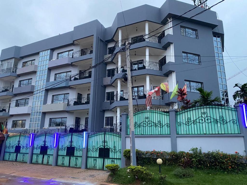 a building with a green fence in front of it at Appart'hôtel Micheline Suites & SPA, Bastos in Yaoundé