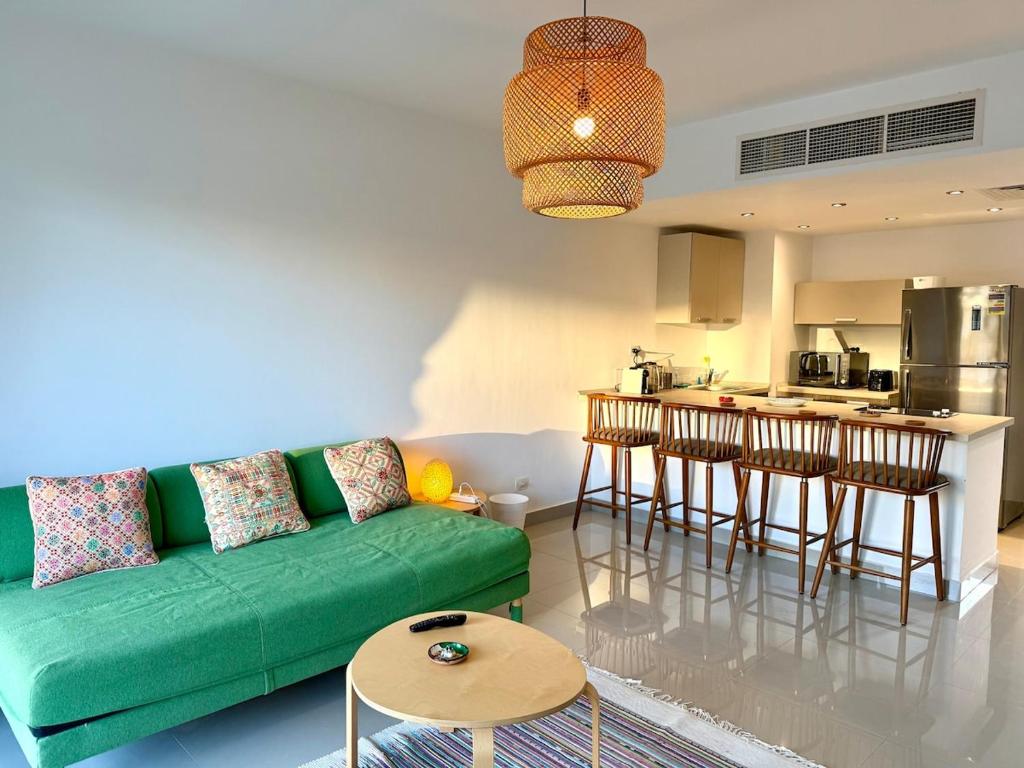 a living room with a green couch and a kitchen at The G Cribs Sunlit - El Gouna in El Gouna
