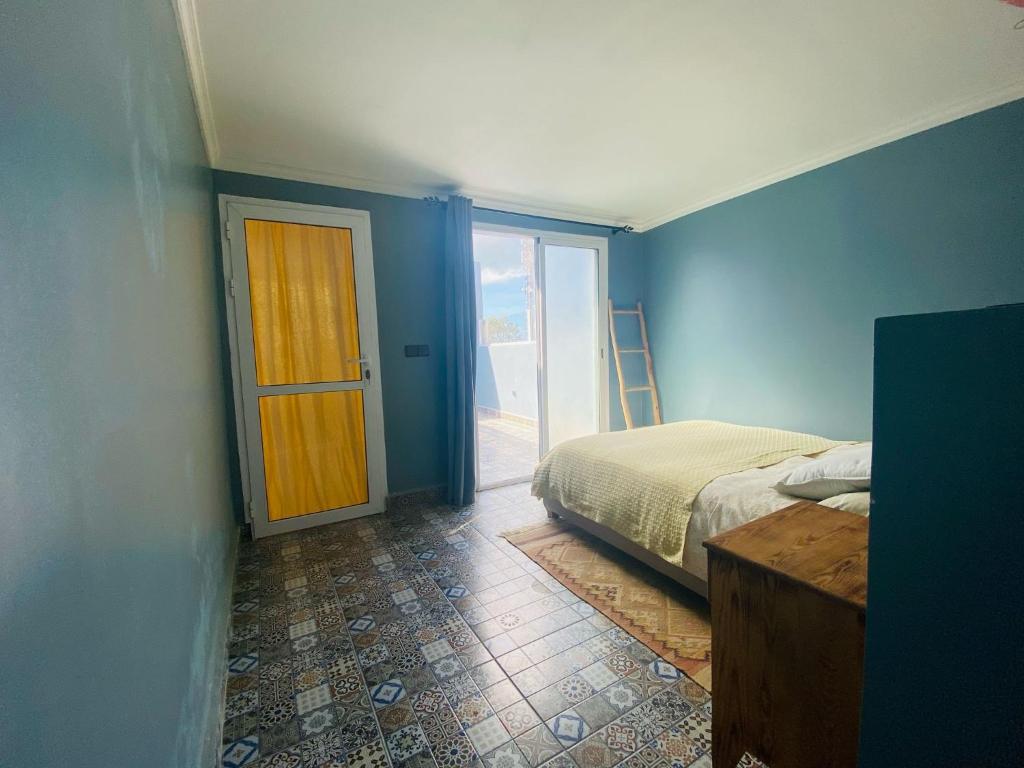 a bedroom with a bed and a door to a balcony at Charming room with balcony and ocean view in Essaouira