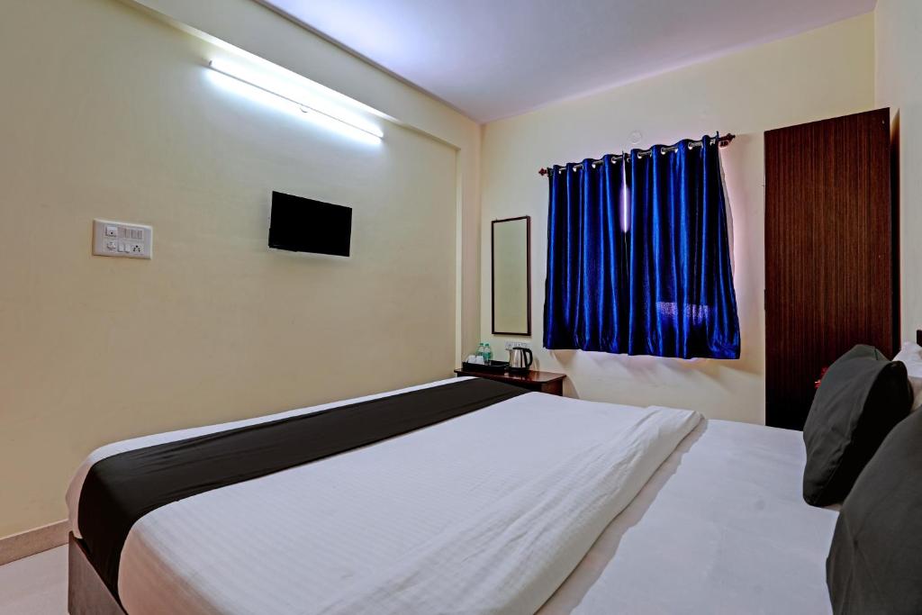 a bedroom with a white bed and a window at Hotel O New Shelton Suites in Bengaluru