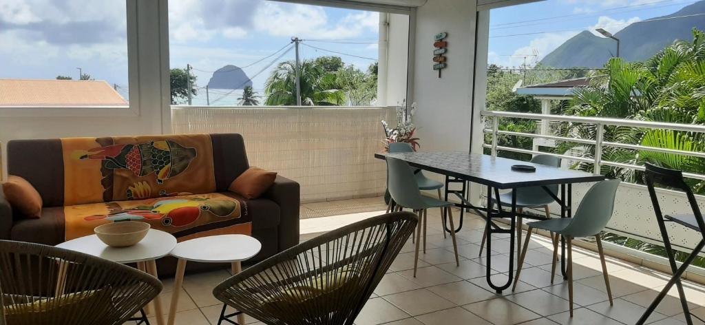 a living room with a couch and a table and chairs at Beau duplex T3 avec une superbe vue mer in Le Diamant