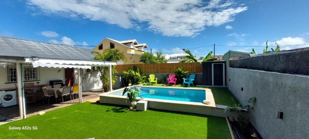 a backyard with a swimming pool and green grass at Villa Hibiscus in Sainte-Anne