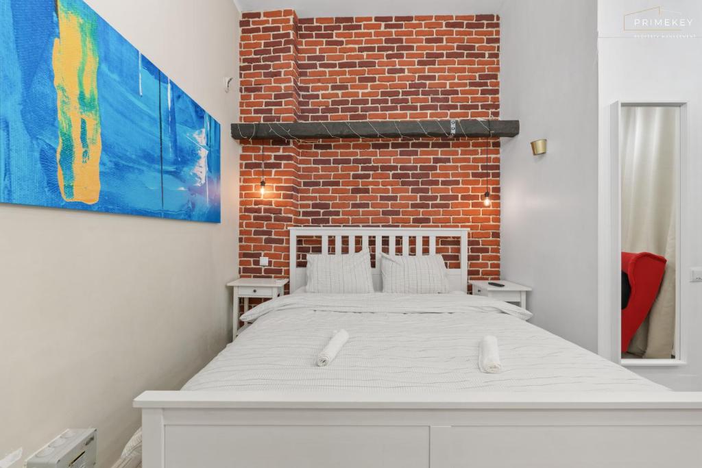 un letto bianco in una stanza con un muro di mattoni di The Brick Loft 1BR Calea Victoriei a Bucarest