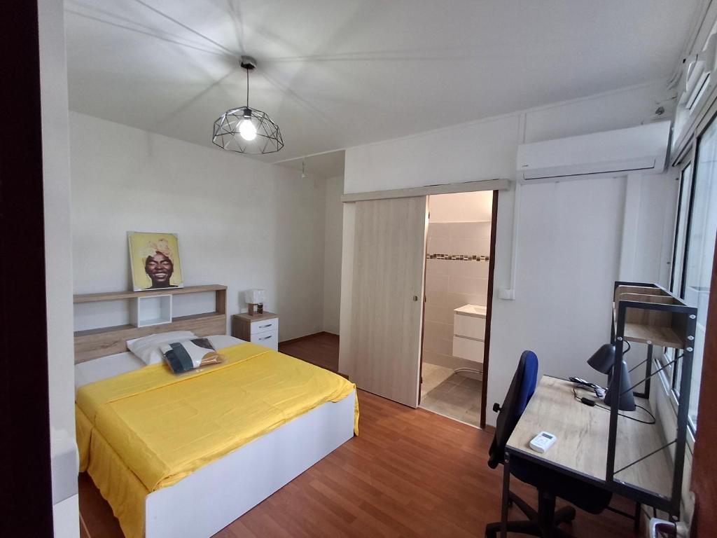 a bedroom with a yellow bed and a desk at Osvalley Résidence in Basse-Terre