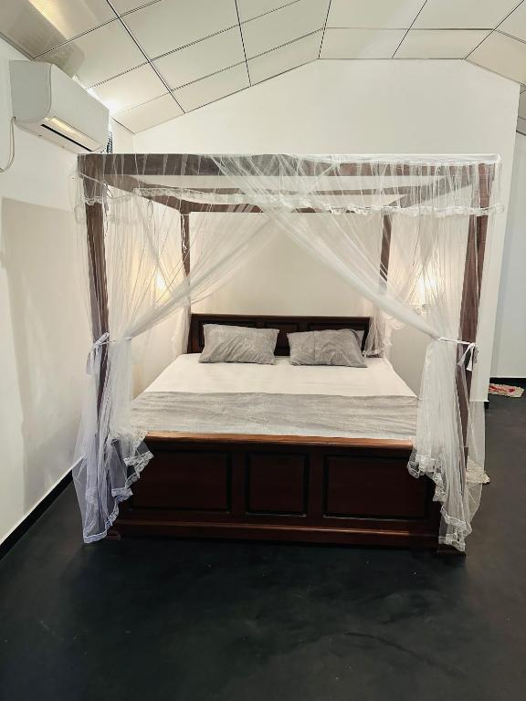 a bed with a canopy in a room at Walwa palm villa in Udawalawe
