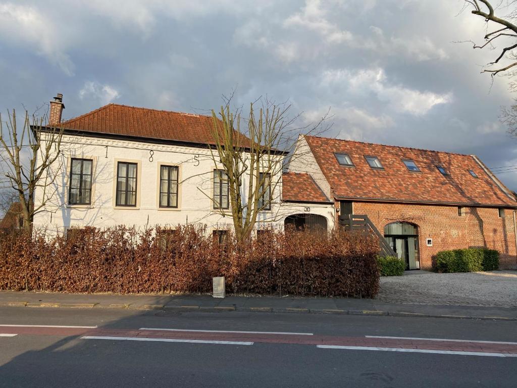 a white building with a red roof on a street at Le426 Charmant T2 bis avec petite cour in Mouvaux