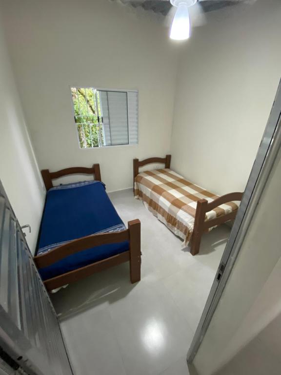 casa de temporada litoral Boraceia Beach - são sebastião في ساو سيباستياو: غرفة نوم بها سريرين ونافذة