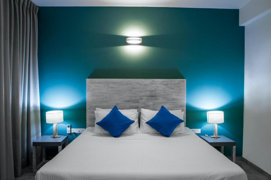 a bedroom with a large white bed with blue walls at Linará in Hikkaduwa