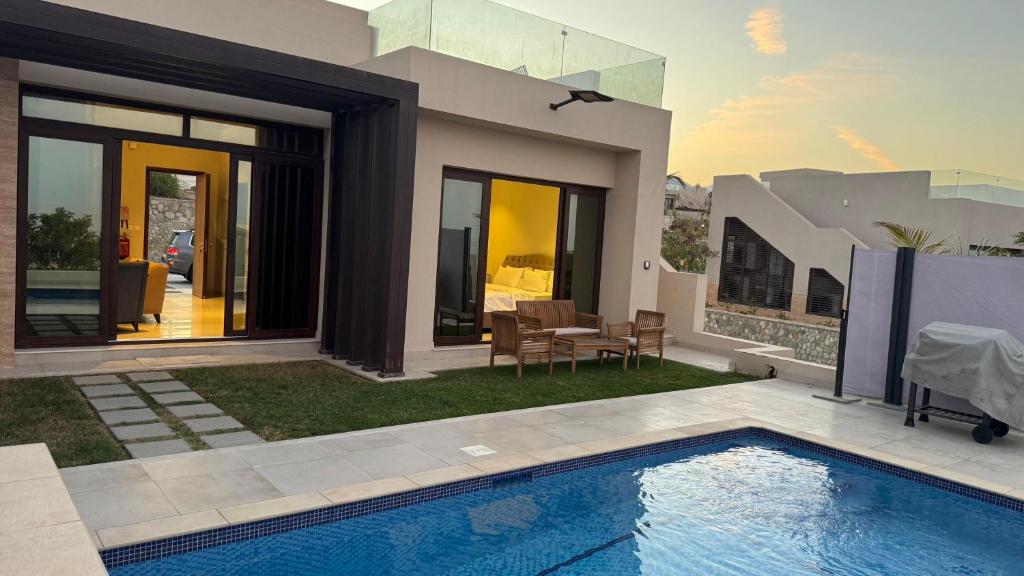 a house with a swimming pool in the yard at The Pearl villa sifah muscat in As Sīfah