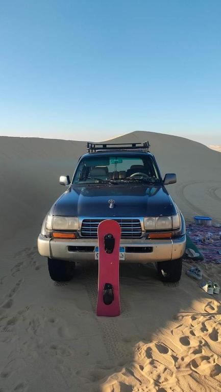 a car parked in the desert with a snowboard on it at White desert Safari tent in Aweina