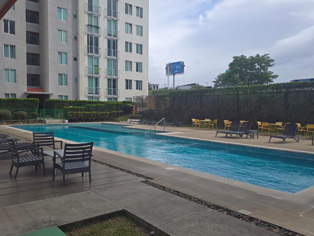 basen z krzesłami i stołami w budynku w obiekcie Bambú Luxury Stay-10 min from Airport w mieście Heredia