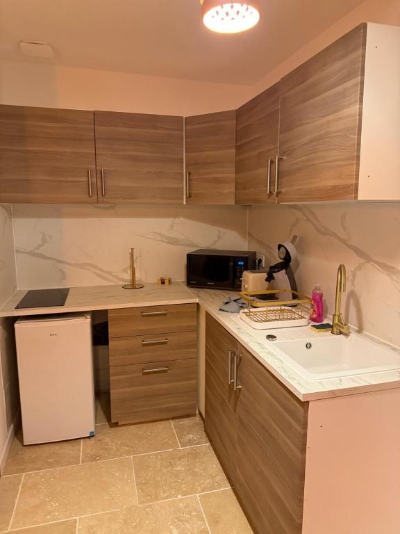 Una cocina con gabinetes de madera y un refrigerador blanco. en César Room - Appartement style grec 2-3 pers, parking, marché de Noël, en Obernai