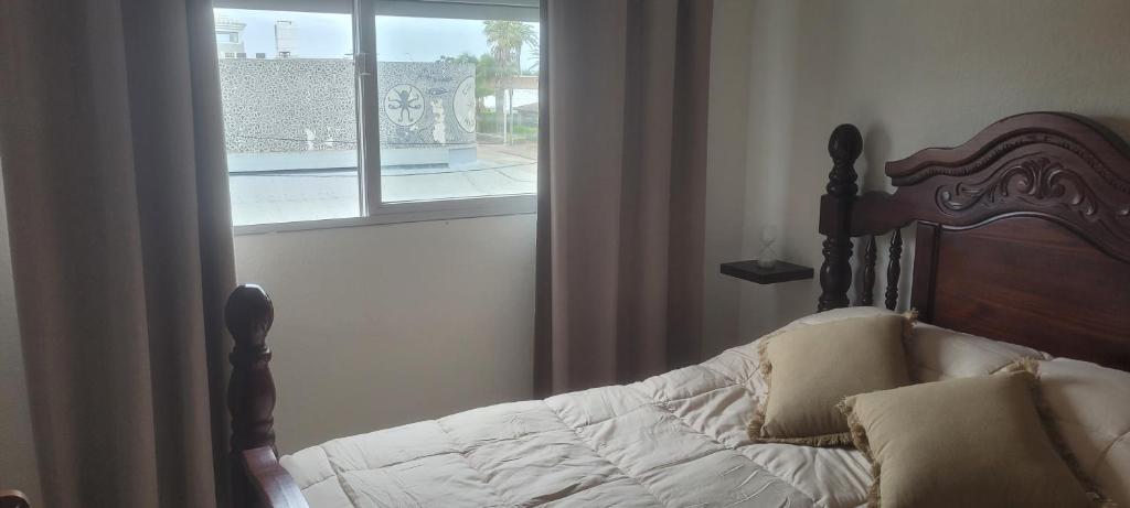 um quarto com uma cama com uma moldura de madeira e uma janela em 4 Mares em Punta del Este