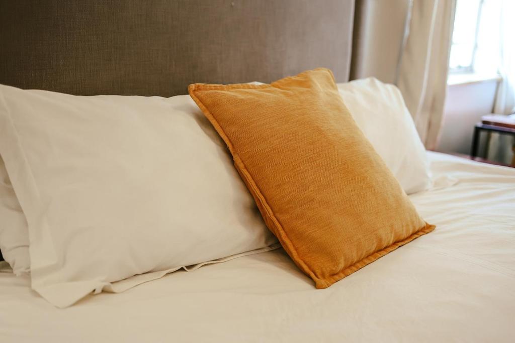 an orange pillow sitting on top of a white bed at Borrowdale Hearthside Retreat in Harare