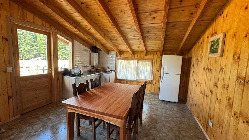 a kitchen with a wooden table and a refrigerator at Departamento a las afueras para 4 in San Martín de los Andes