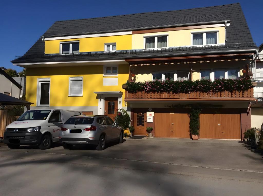 GebhardsweilerFerienwohnungen Sick的两辆汽车停在黄色房子前面